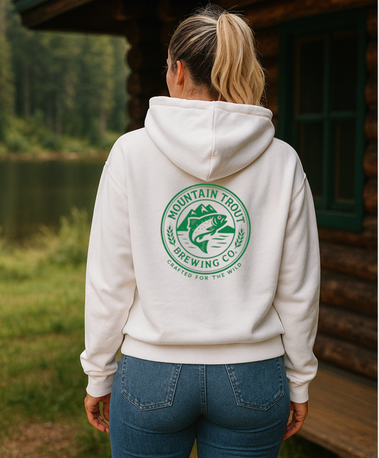 Person wearing a white hoodie with a logo in a natural setting